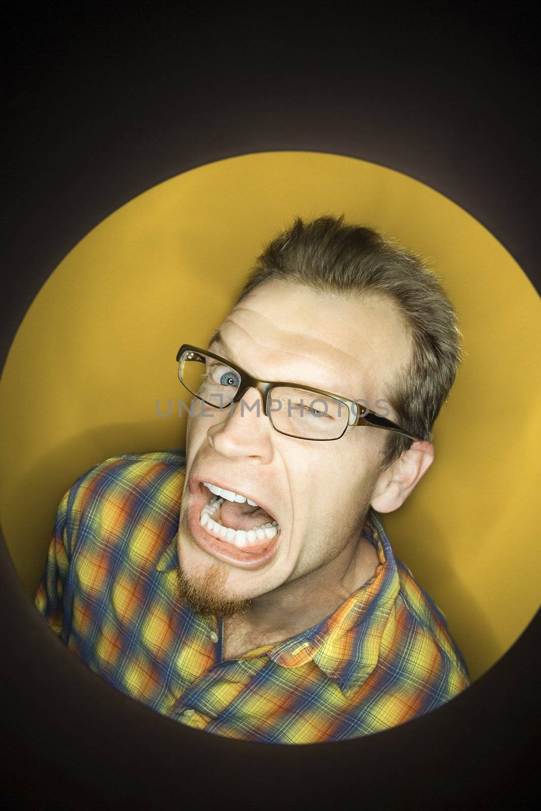 Vignette of adult Caucasian man on yellow background winking and making funny face.