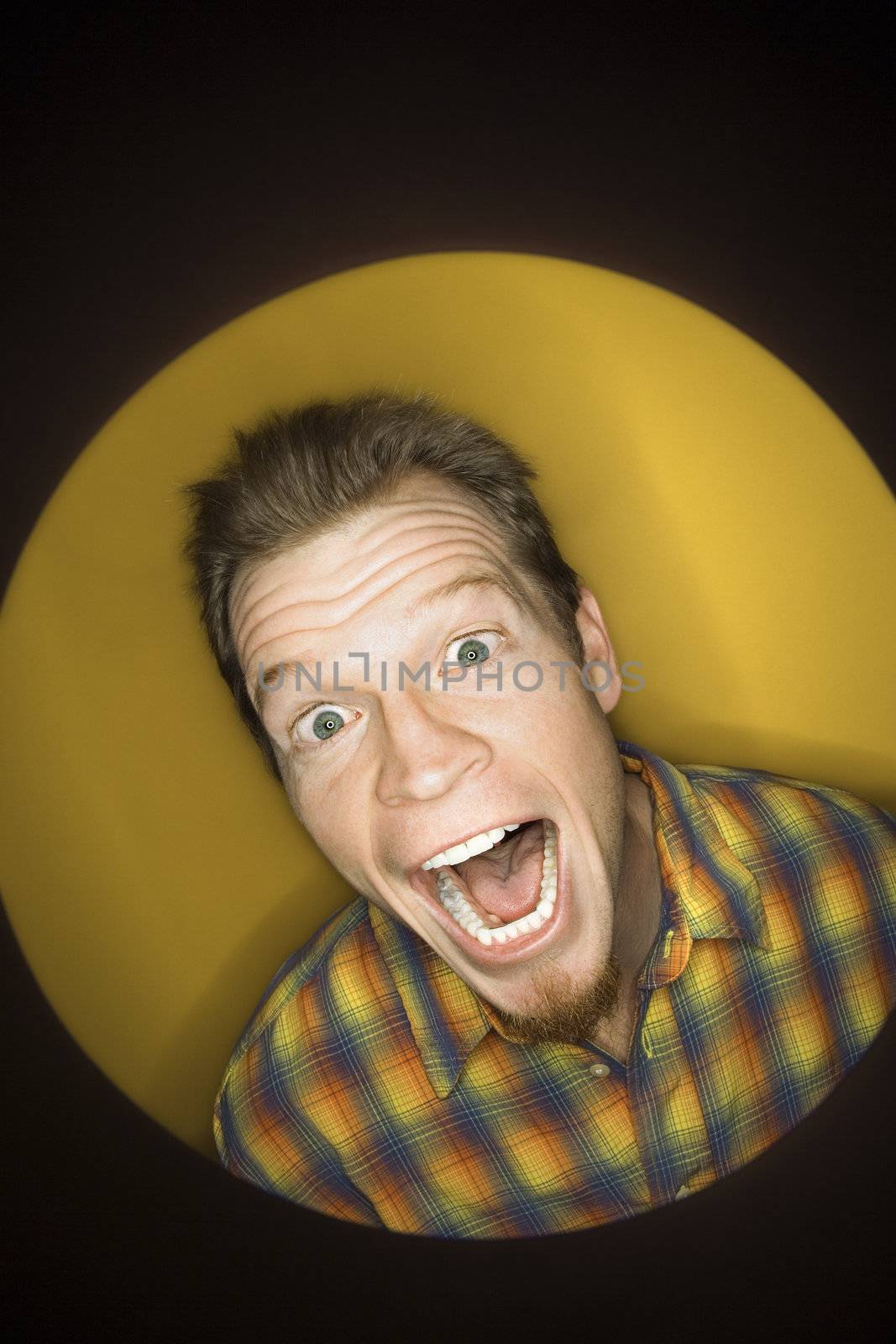 Vignette of adult Caucasian man on yellow background making funny face at viewer.