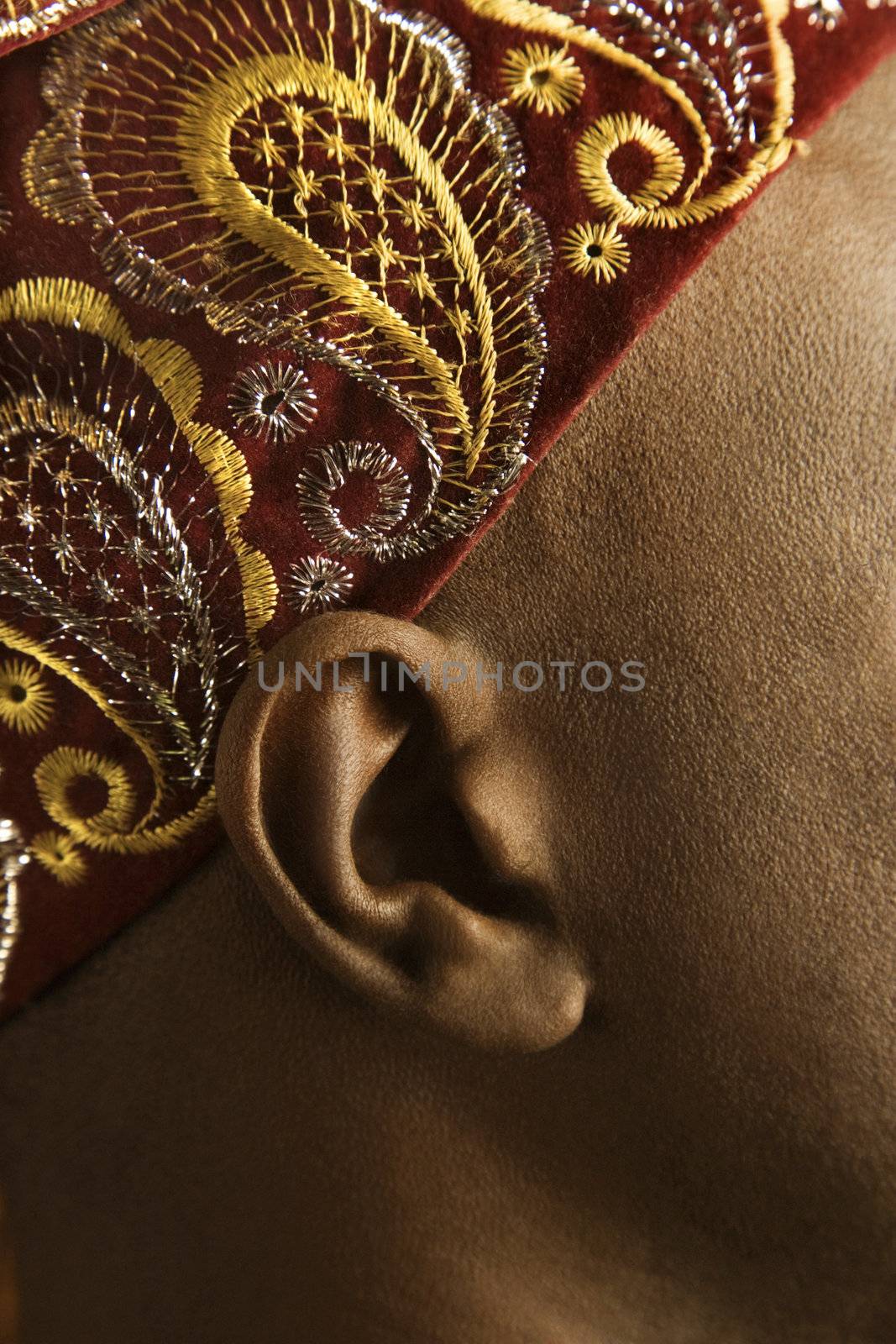 Close-up side view of African-American mid-adult man wearing traditional African hat.