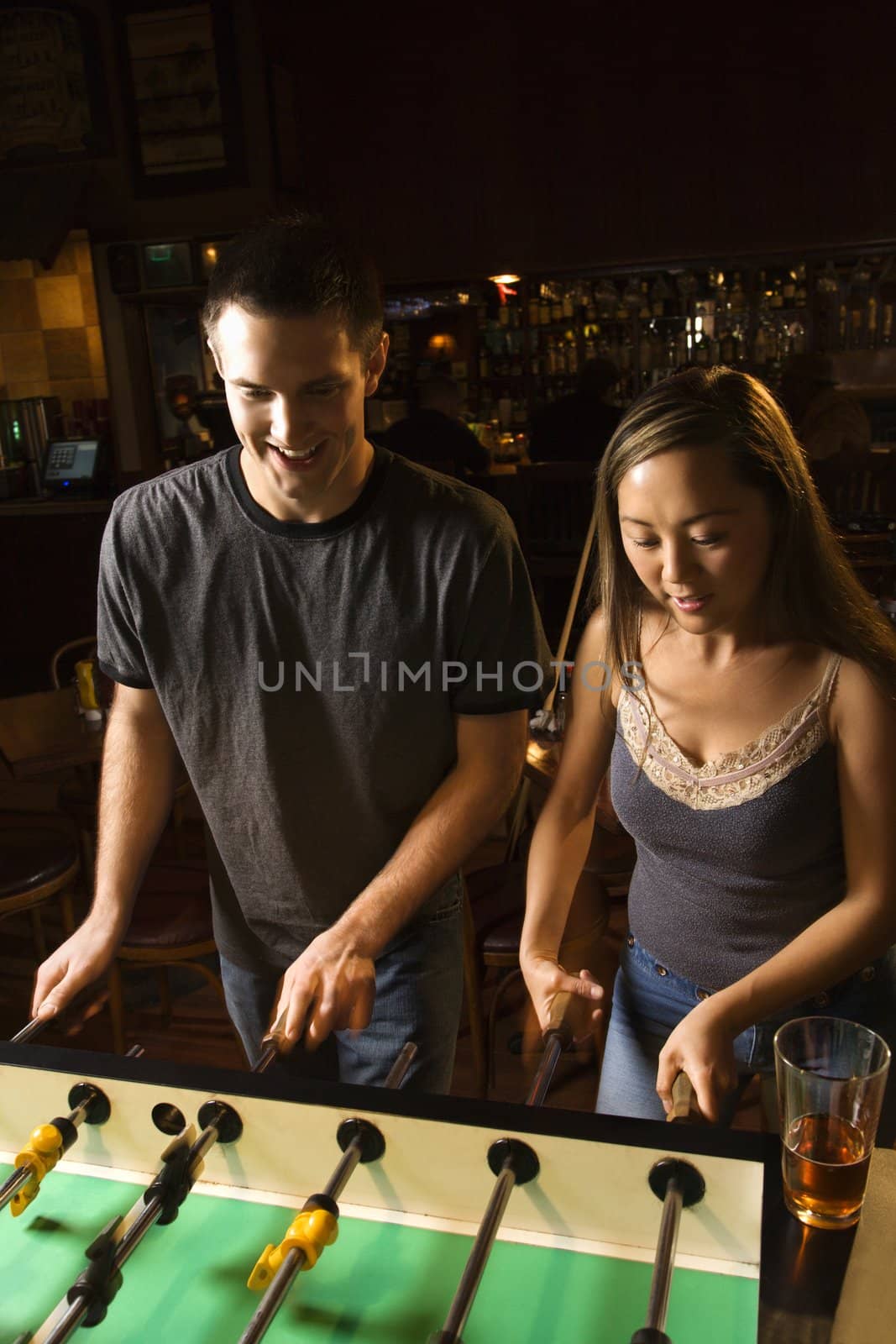 Young couple teamed up at foosball game in pub.