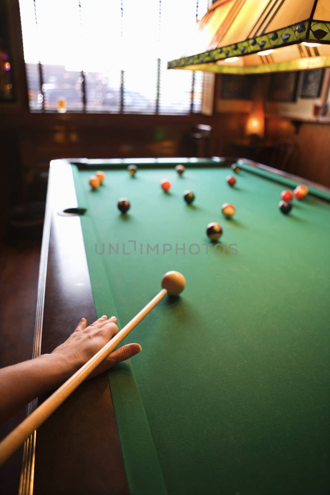 Woman's hand preparing to hit pool ball while playing billiards.