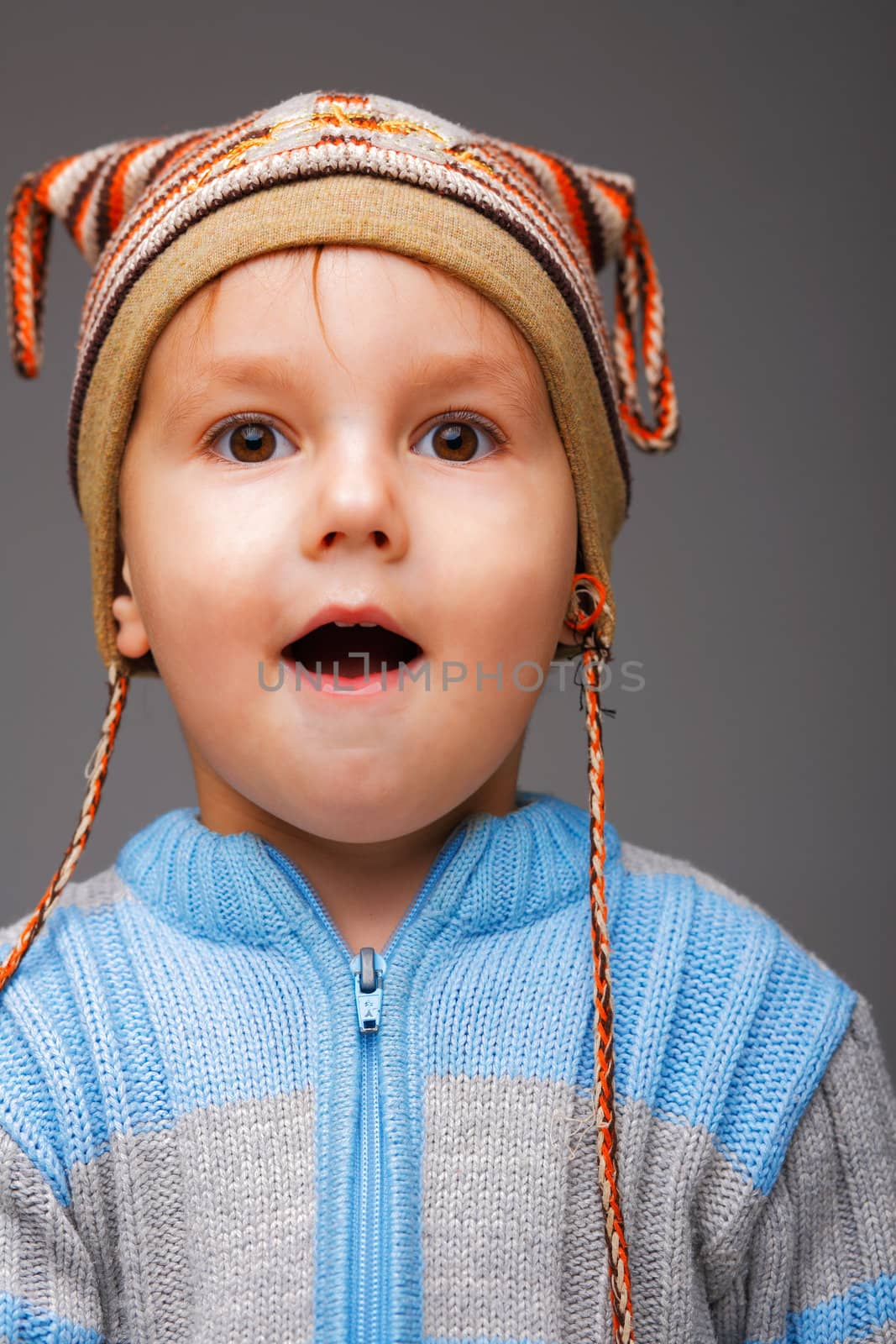 Closeup portrait of a little boy in a nice striped cap enjoying something he has just seen