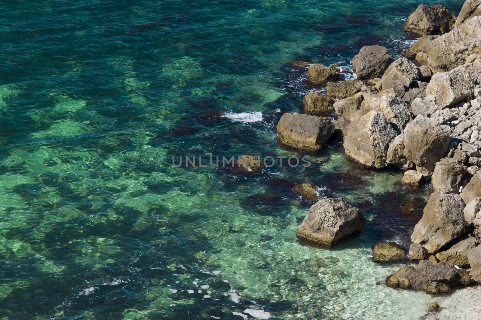 rocky coast with green-blue transparent sea water