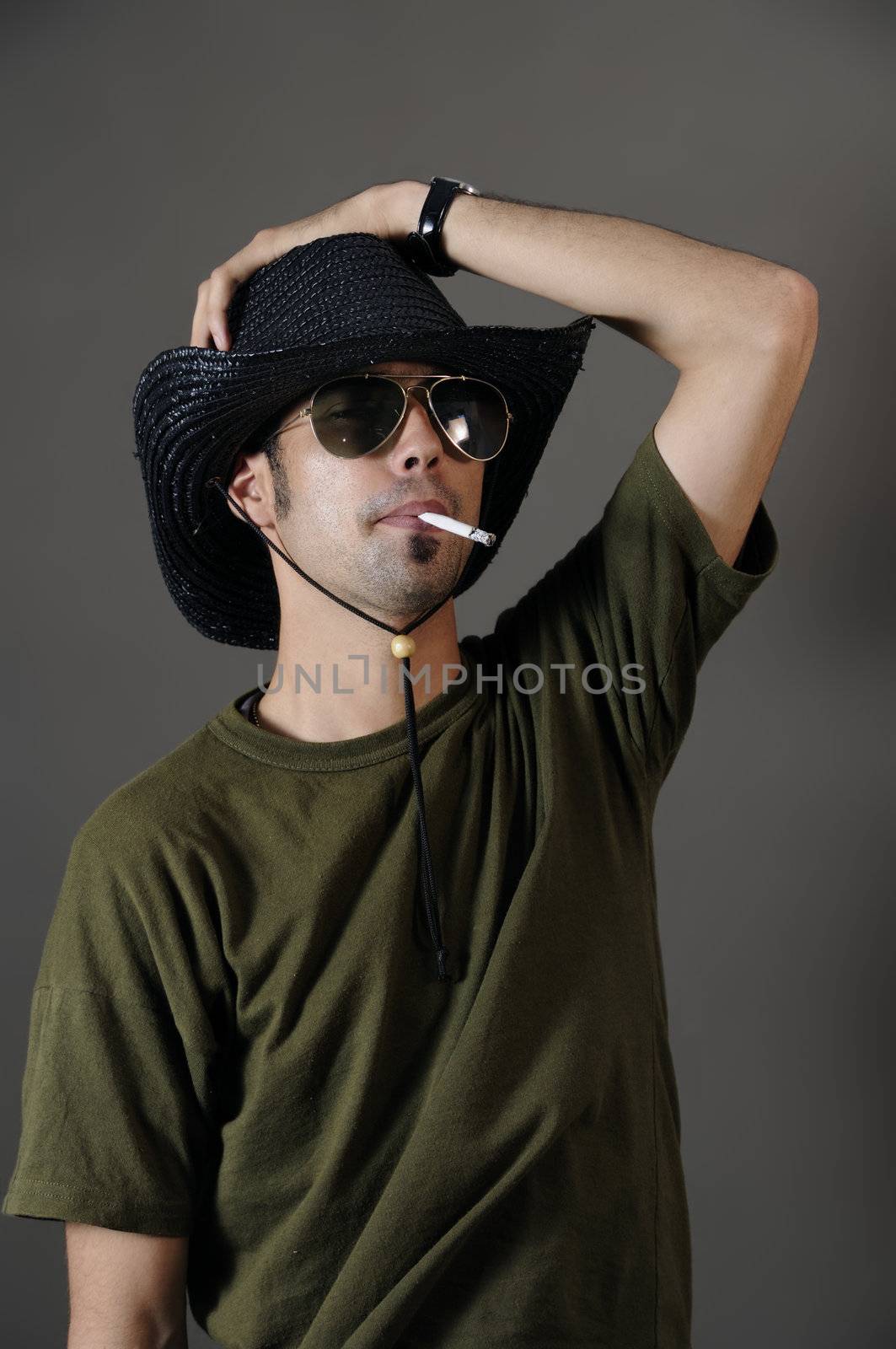 Portrait of young male smoking with sunglasses and cowboy hat