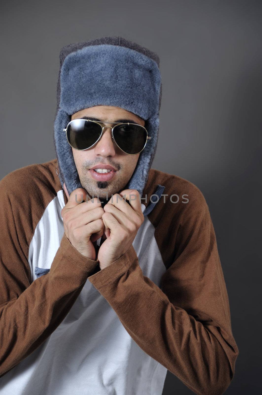 Portrait of young trendy guy in sunglasses and winter hat