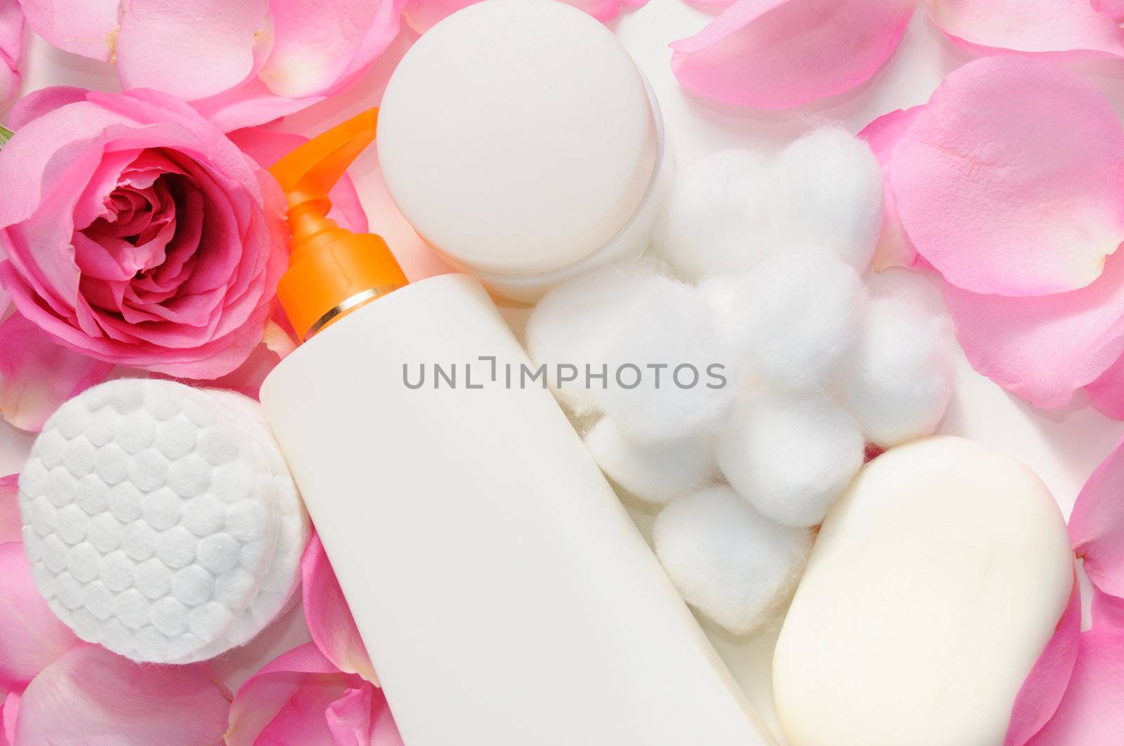 Skin care products with rose petals and cotton swabs