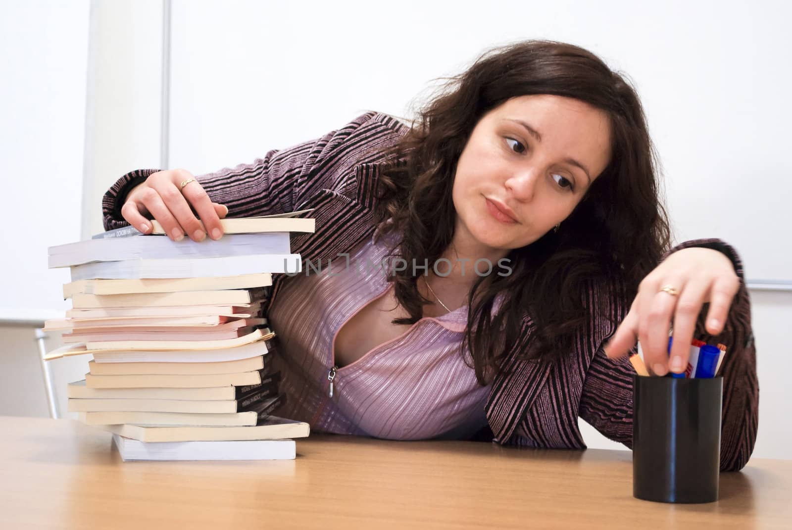 young student holding her head over books