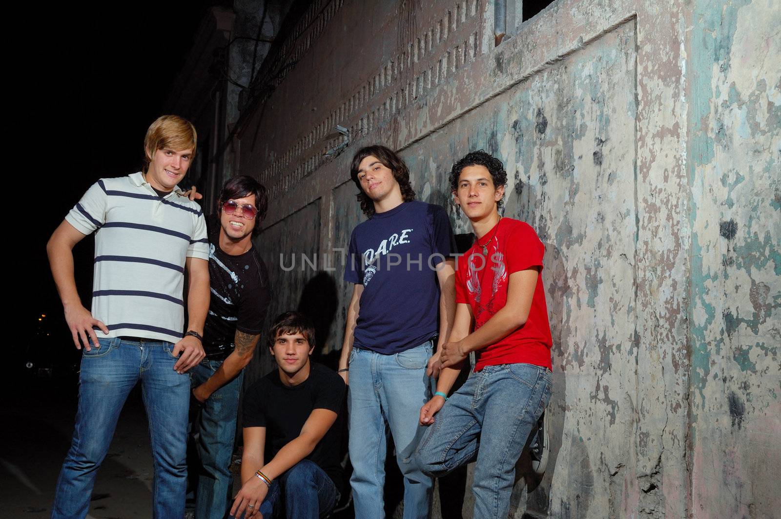 Team of young trendy teenagers against grunge wall