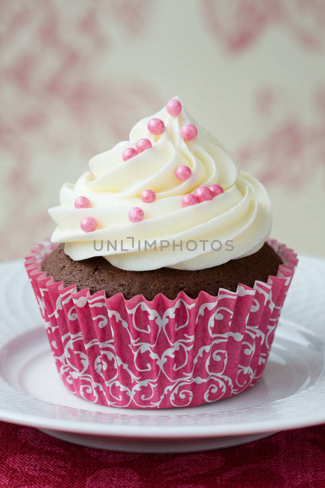 Chocolate cupcake decorated with frosting and pink dragees