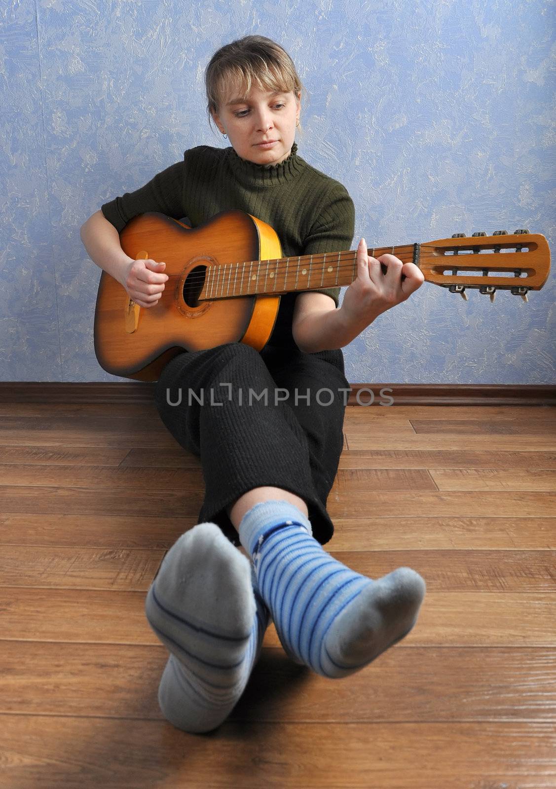 Woman with guitar in house on floor sits