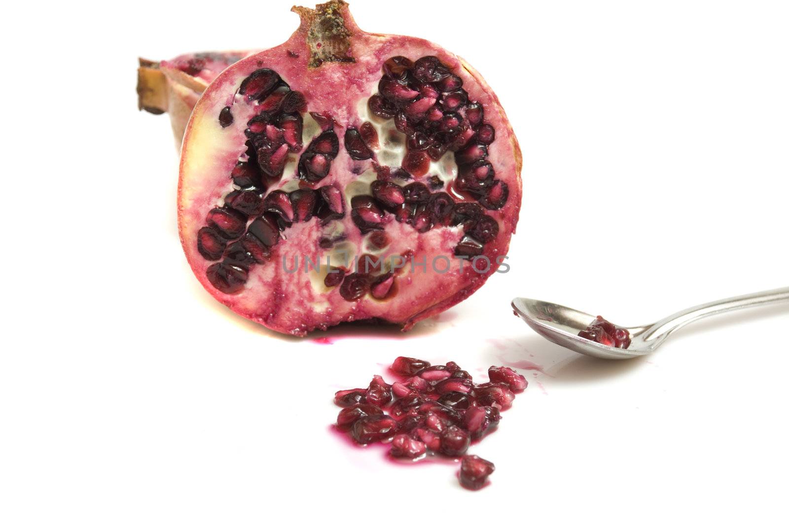 Close-up on a fresh pomegranate with yummy juice and sweet and sour seeds, isolated on white