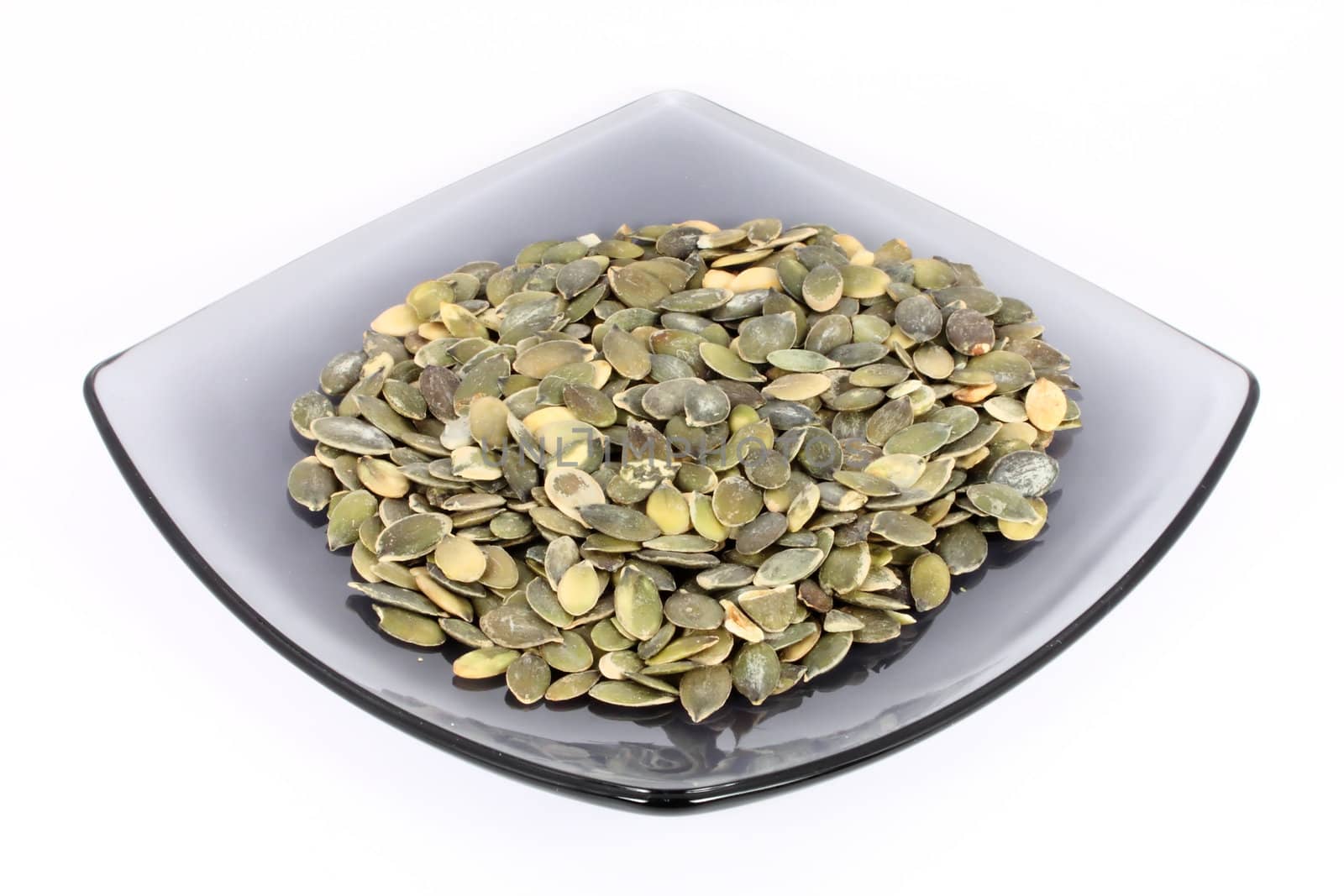 Pumpkin seed on glass plate, isolated on white