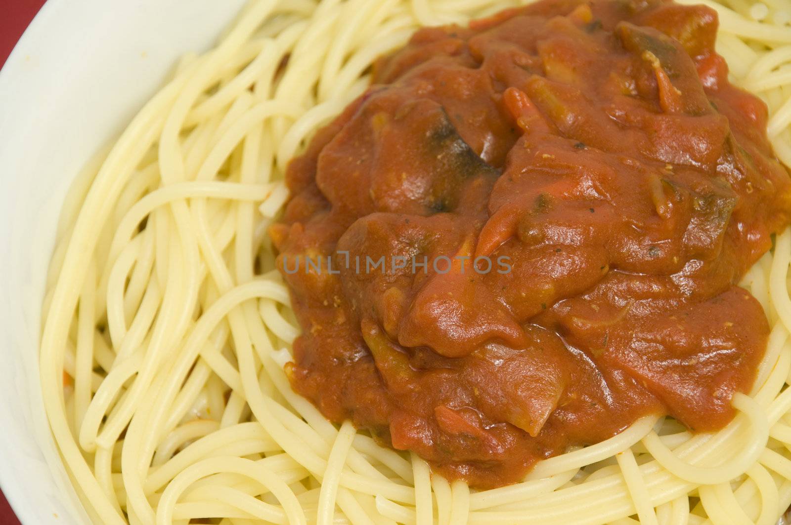 close-up on a full bowl of pasta with meat, vegetables, sauce, spices and cheese