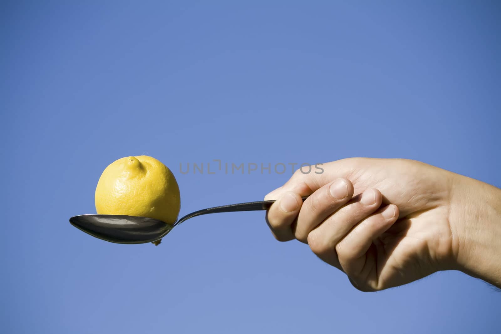 lemon and spoon against blue sky by nubephoto