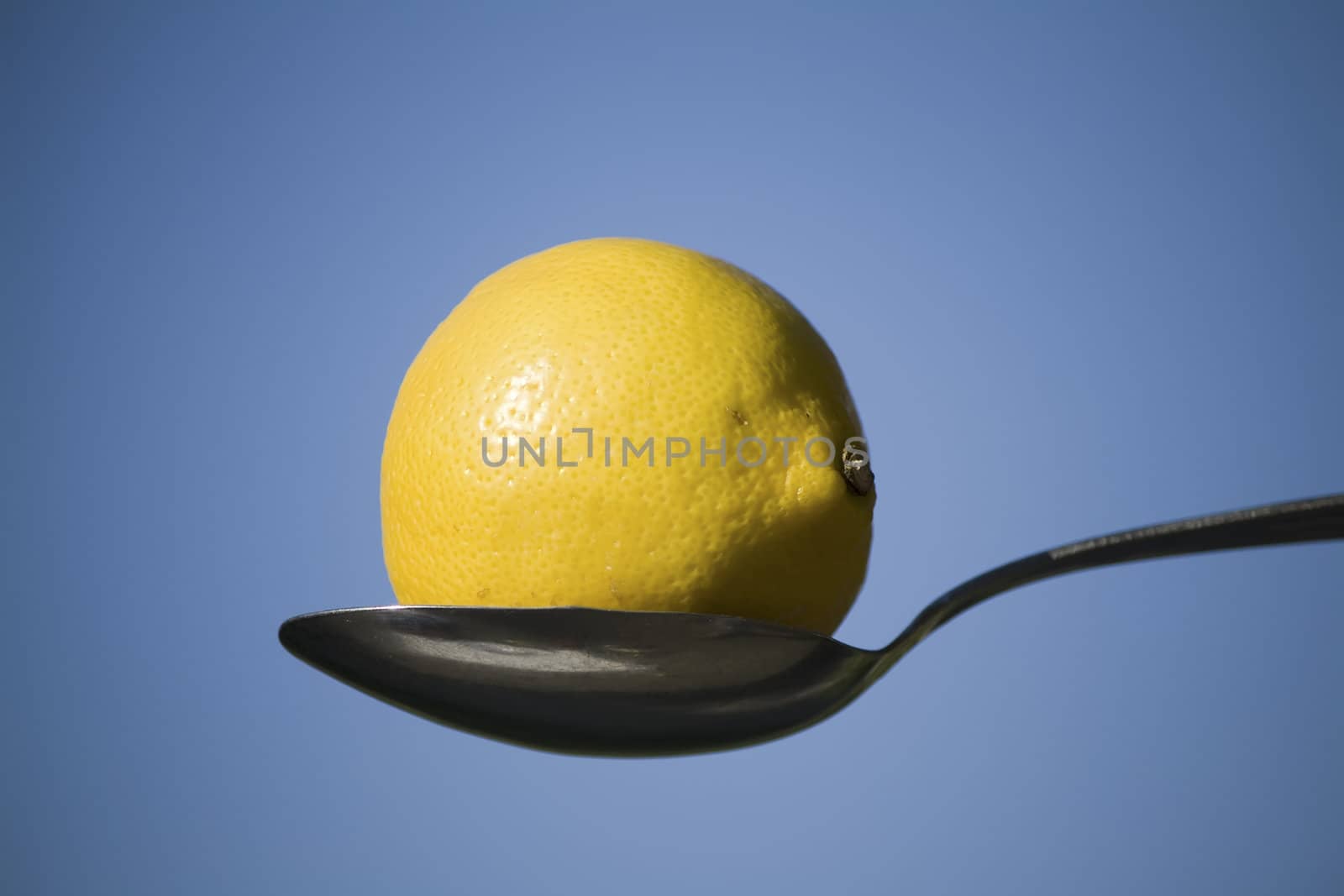 lemon and spoon against blue sky by nubephoto