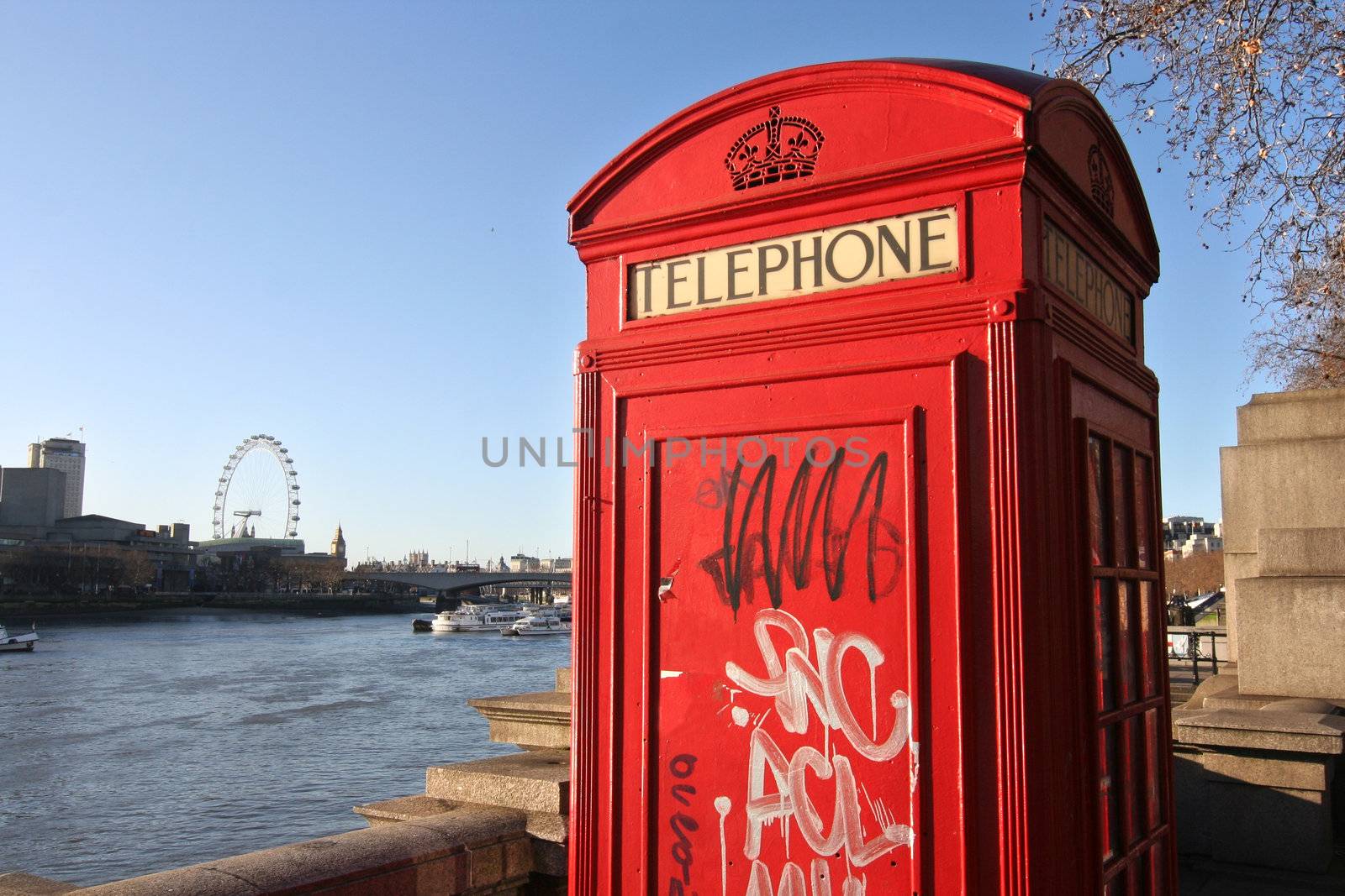 London: traditional telephone box along the Thames, sprayed with graffiti