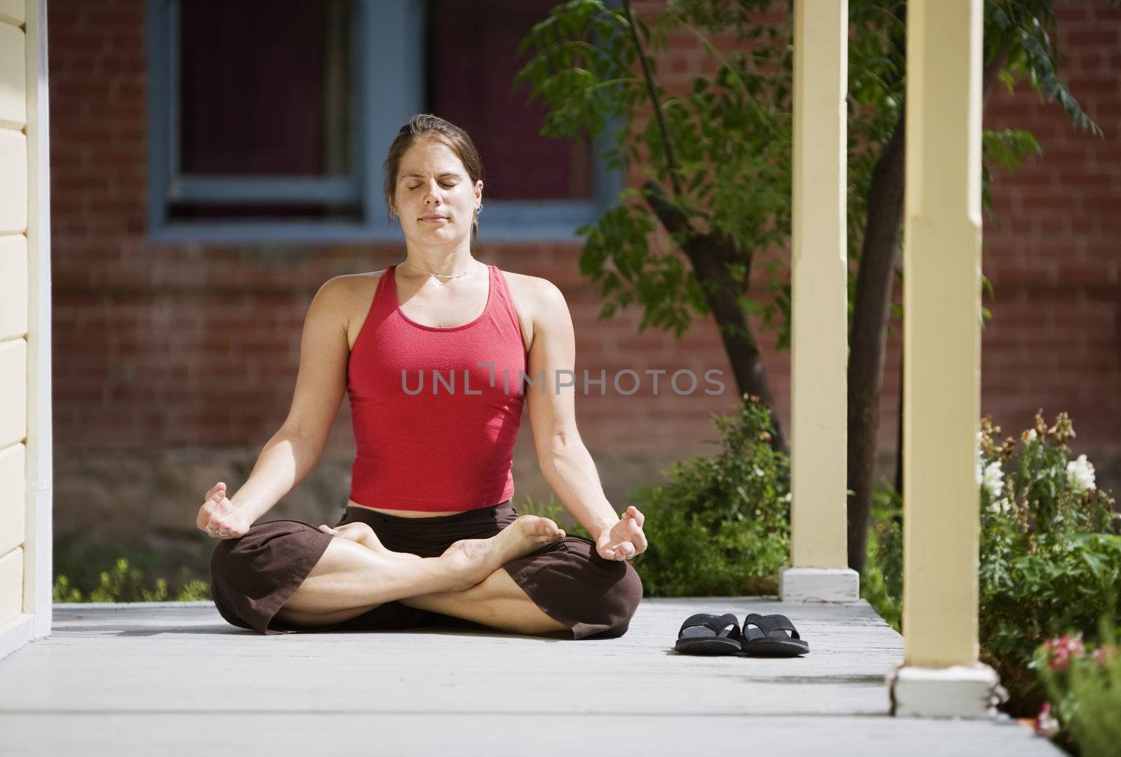 Pretty Young Woman in the Lotus Position on a Porch