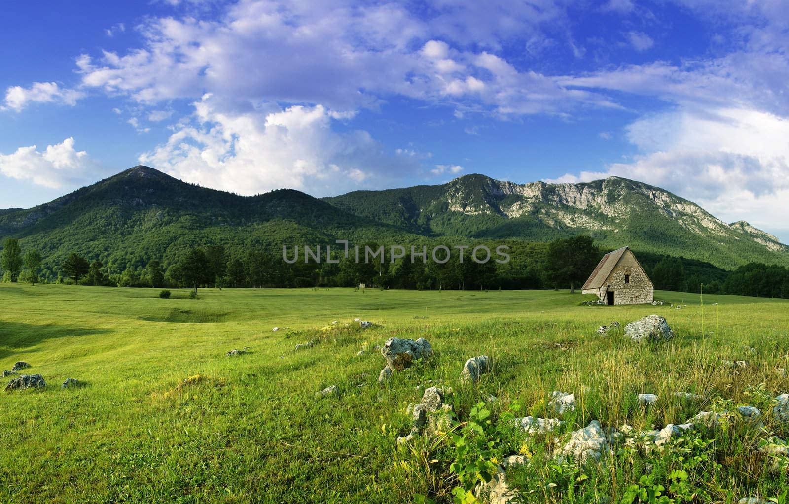 rural landscape with old house on the field over mountains 