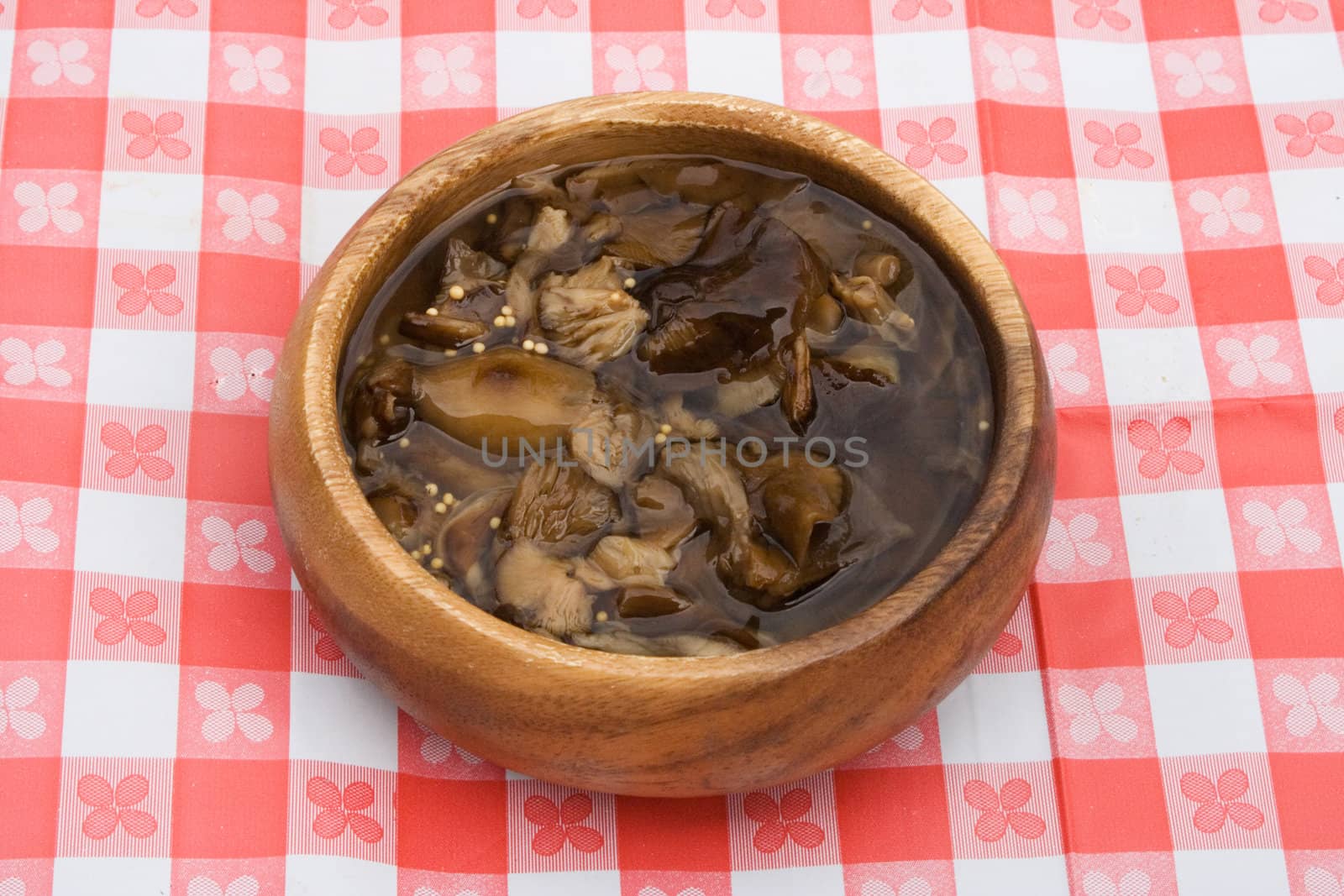 a bowlful of marinated mushrooms on a table cowered with checkered buckram