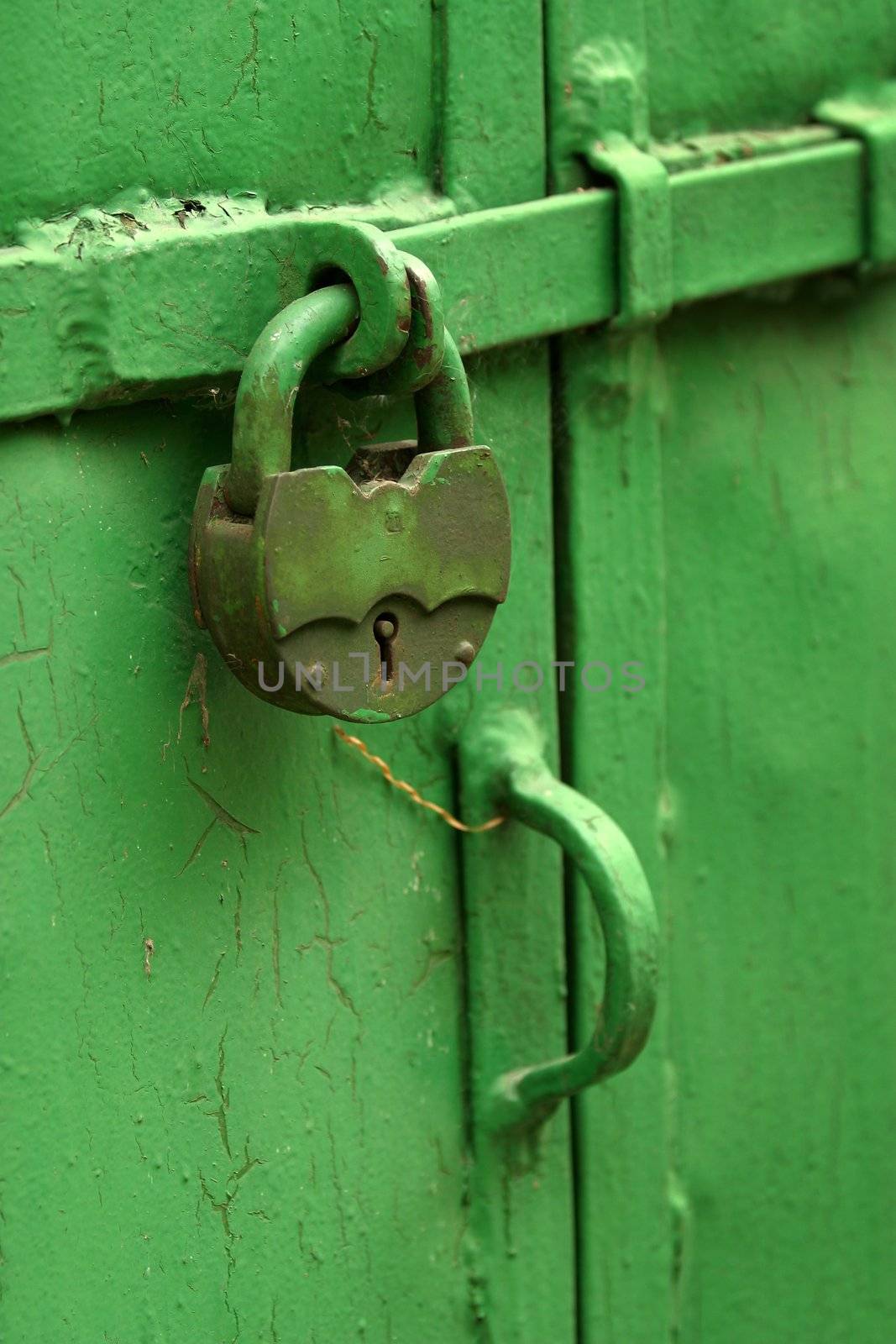 The rusty lock on a green door