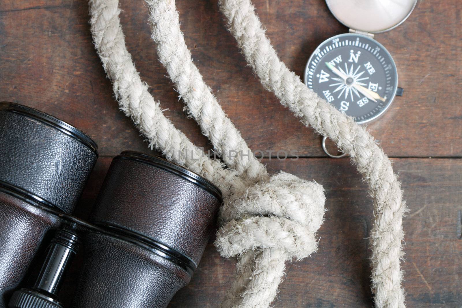 Still life with antique binoculars, rope and compass on wooden background