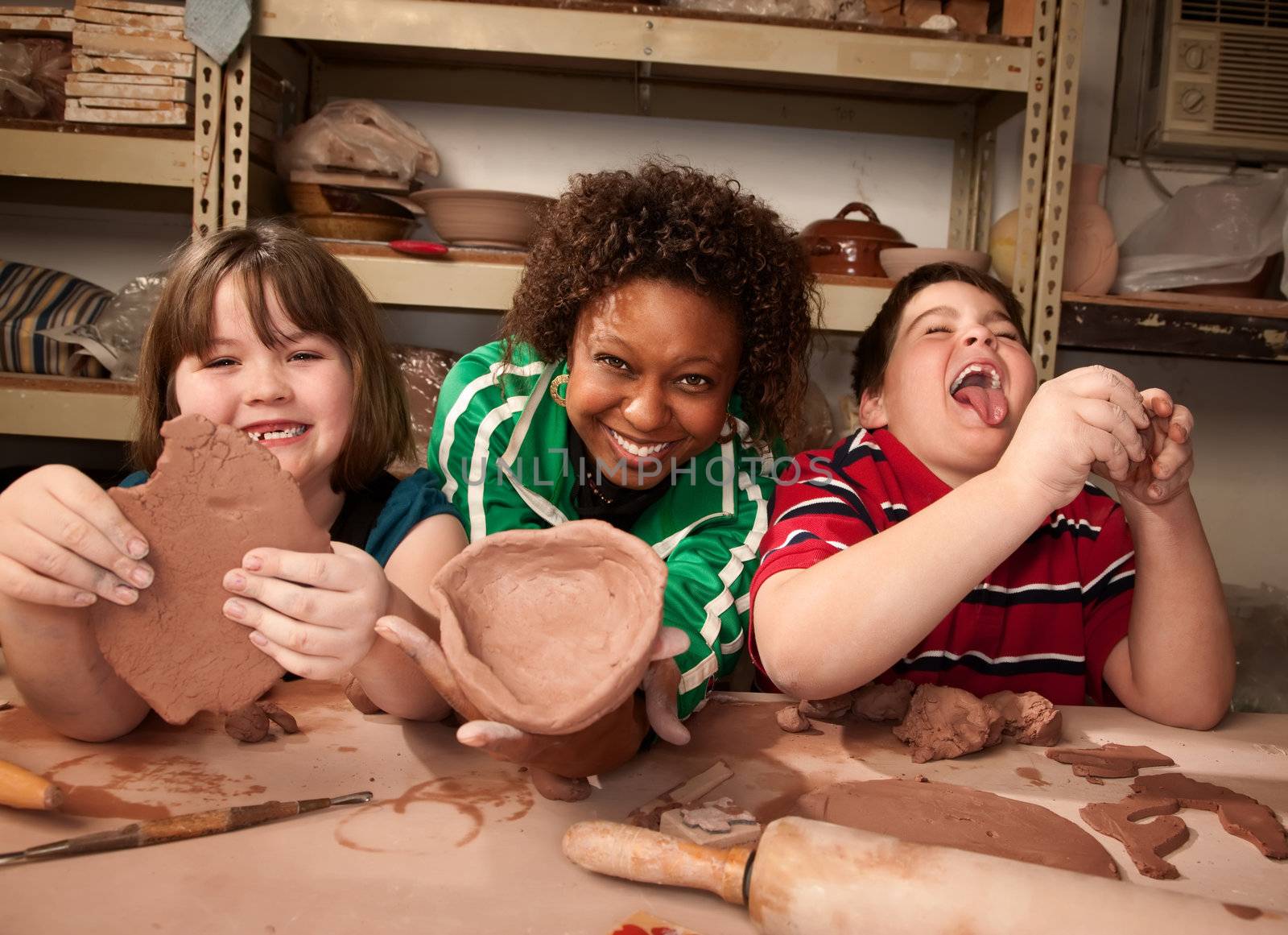 Teacher and young students working on projects in clay studio