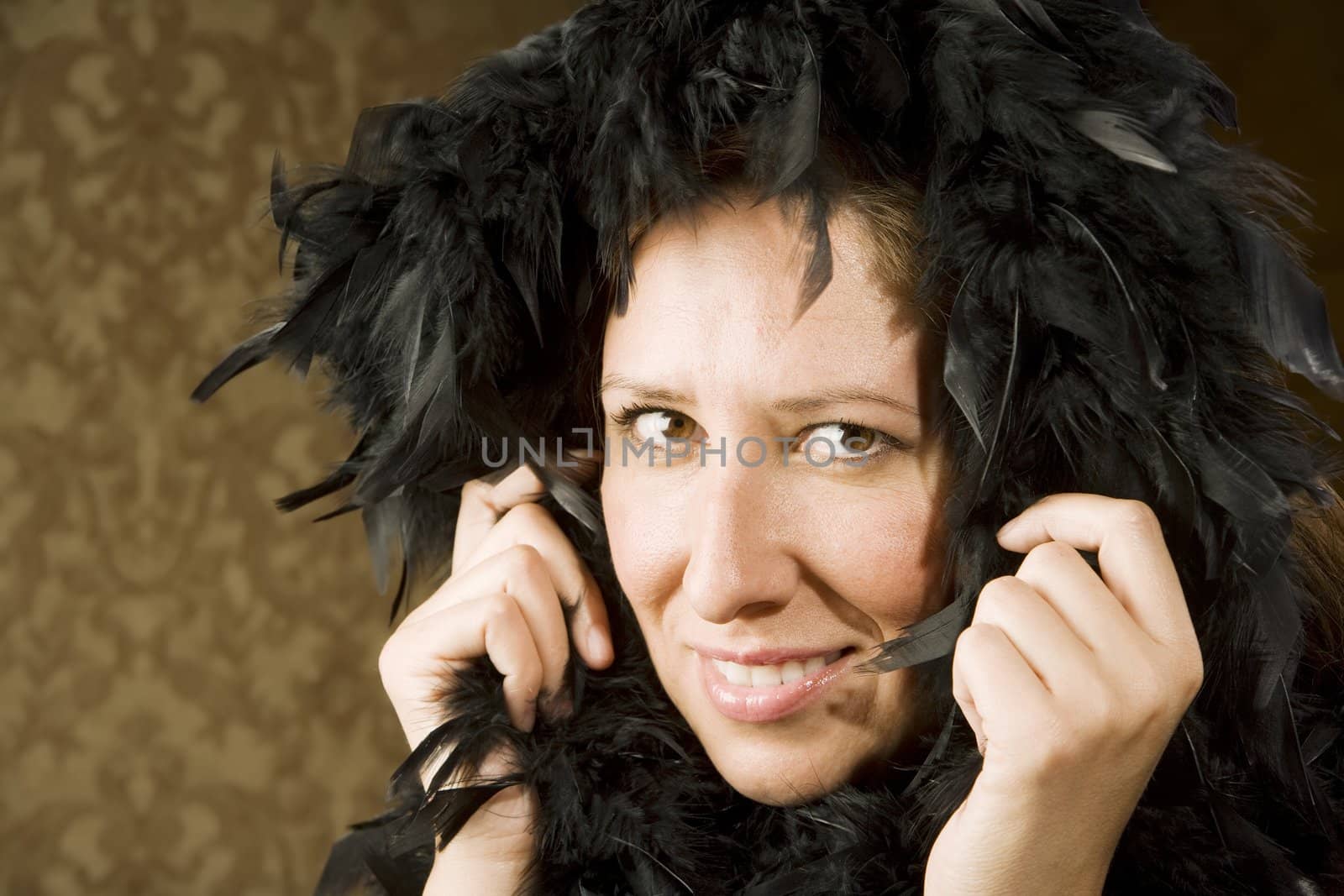 Pretty Hispanic Woman Wearing a Feather Boa in front of Gold Wallpaper