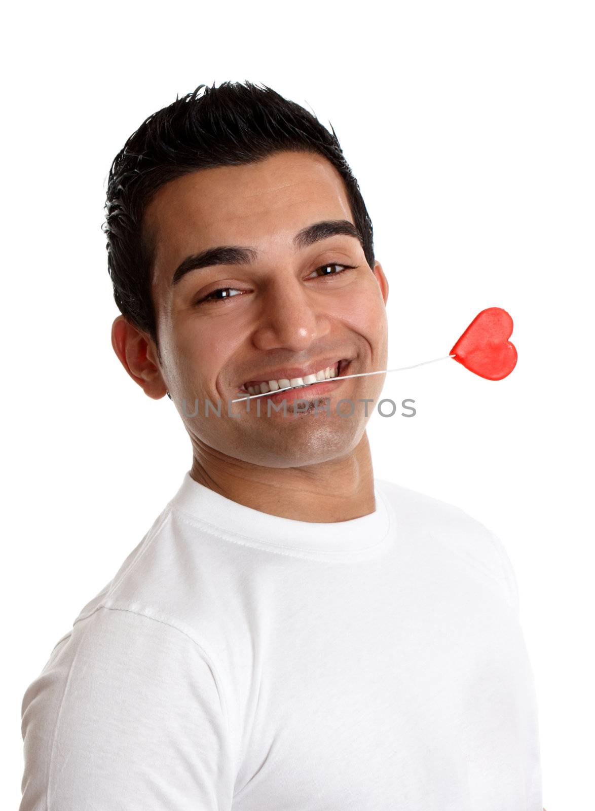 A romantic man holds a red love heart on a stick between his teeth