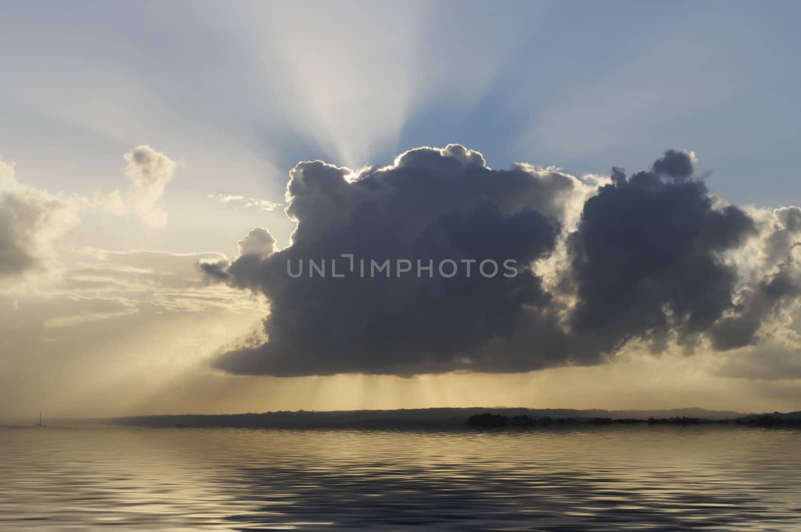 sun is breaking through a dark cloud over  calm water