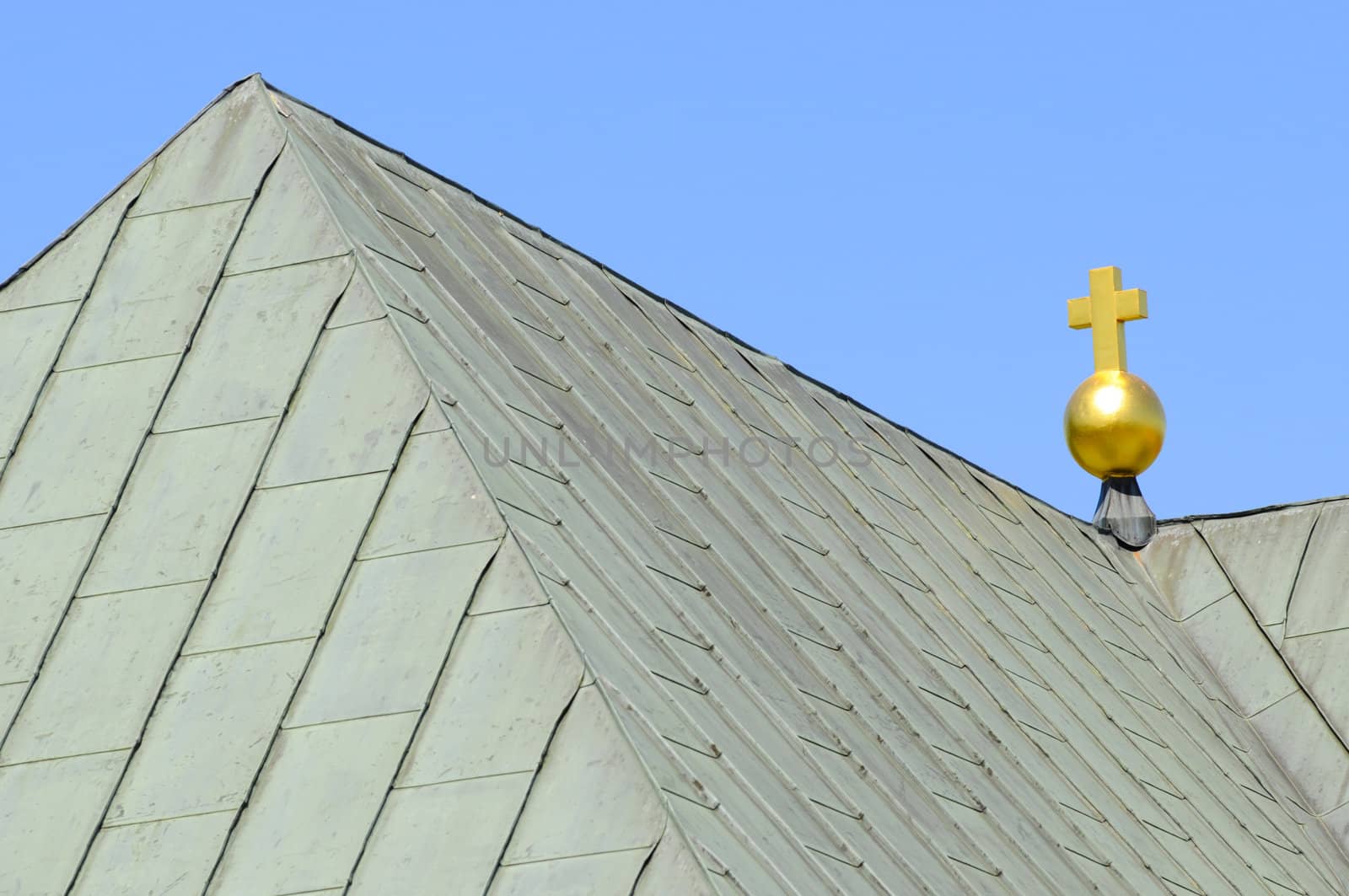 golden cross on top of sheet metal church roof