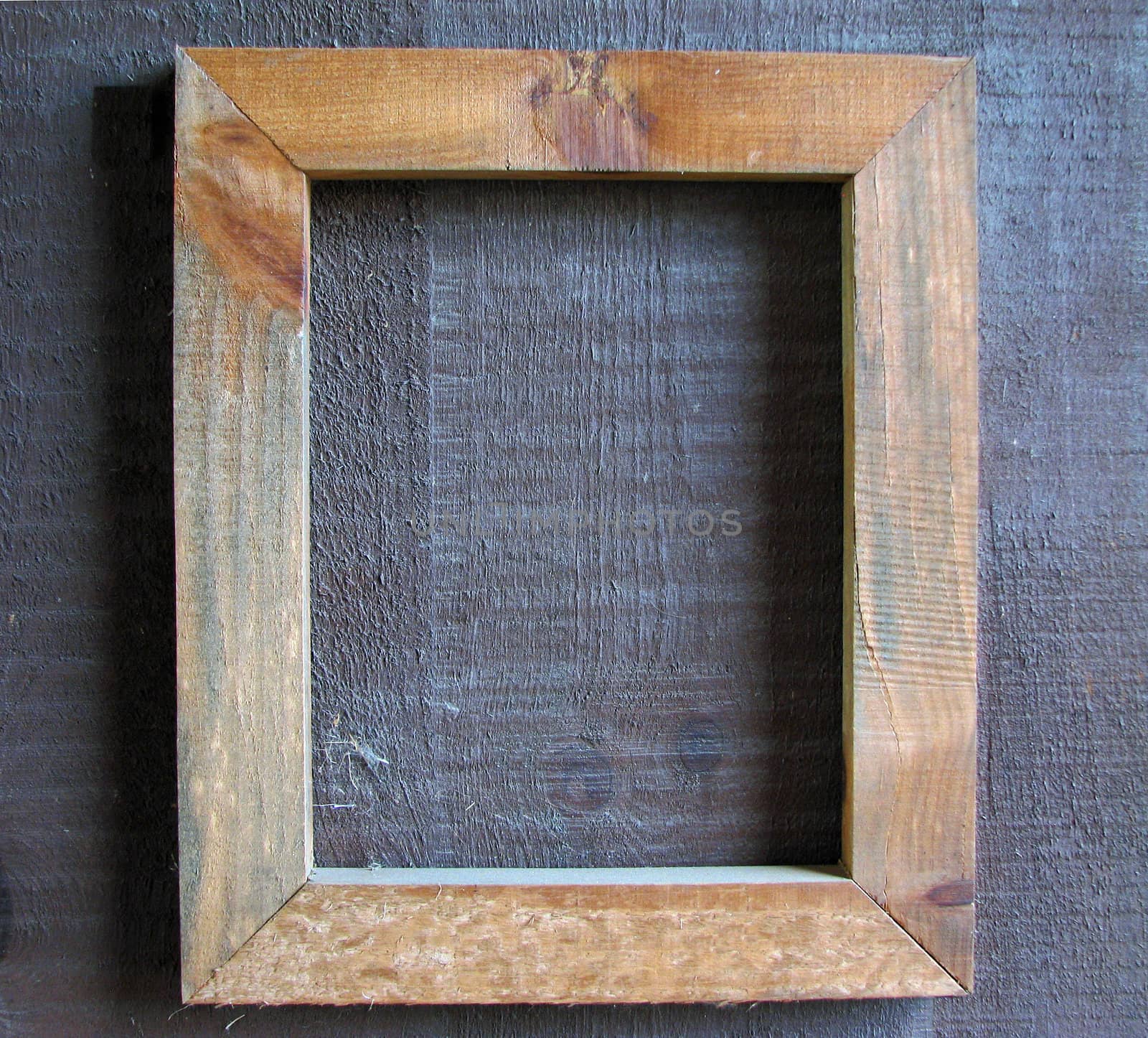 An empty wooden frame on a wooden wall.
