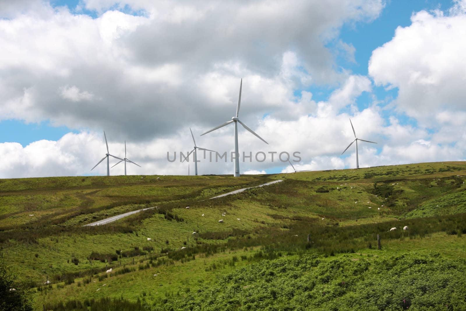 Wind Farm Power Turbines Carno Wales UK against a blue sky with black clouds,rural sheep farming area