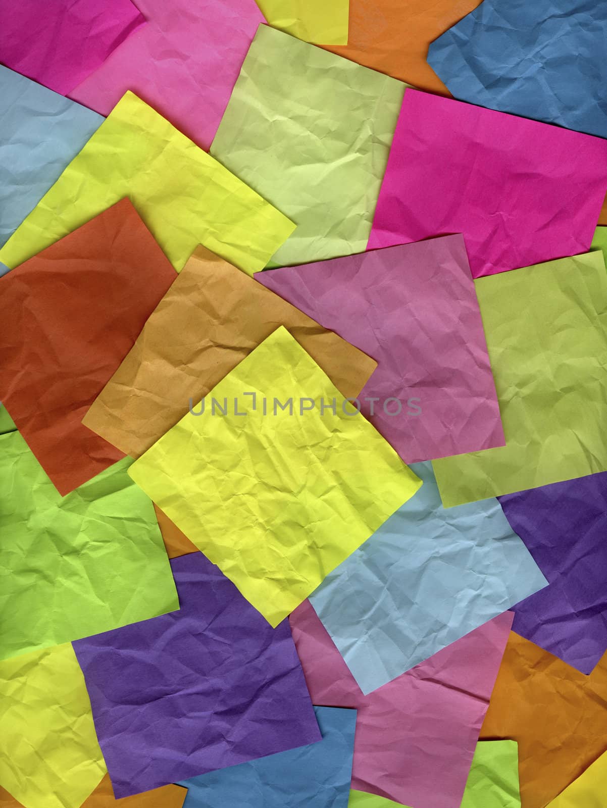 blank yellow sticky note on top of background of crumpled colorful notes