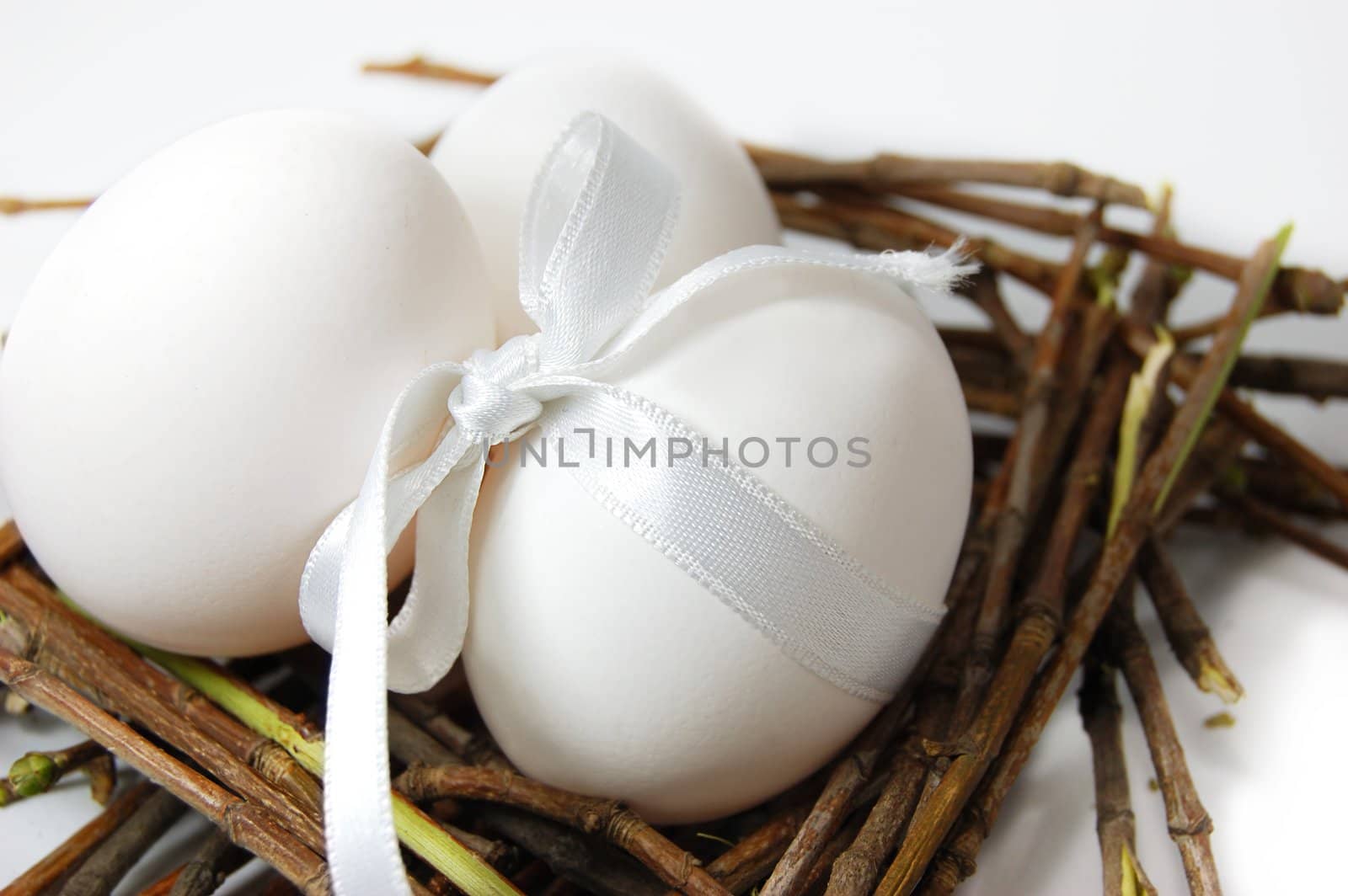white eggs with ribbon in nest on white
