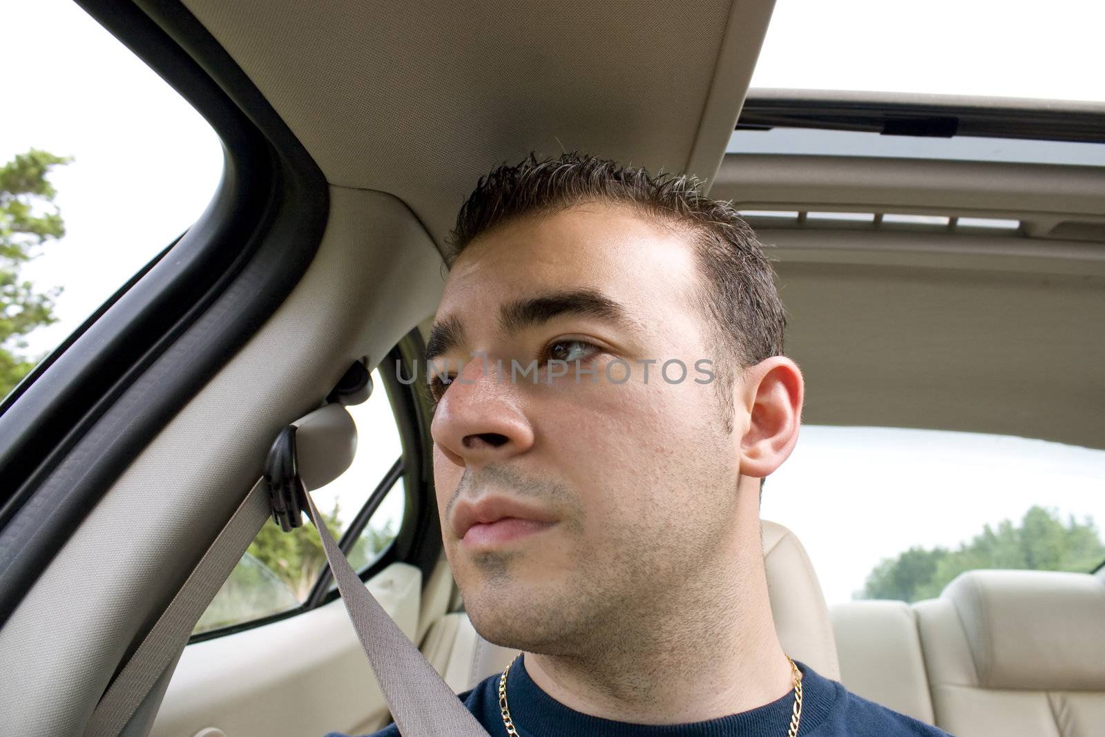 A young man is bored and stares out the window while riding as a passenger on a long road trip