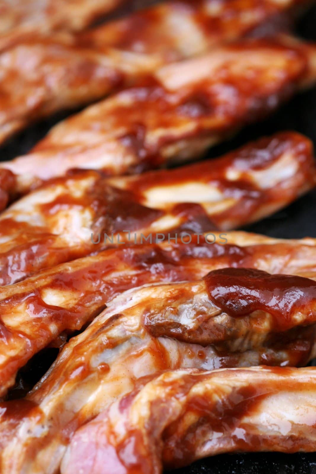 Ribs covered with barbecue sauce sizzling on the BBQ