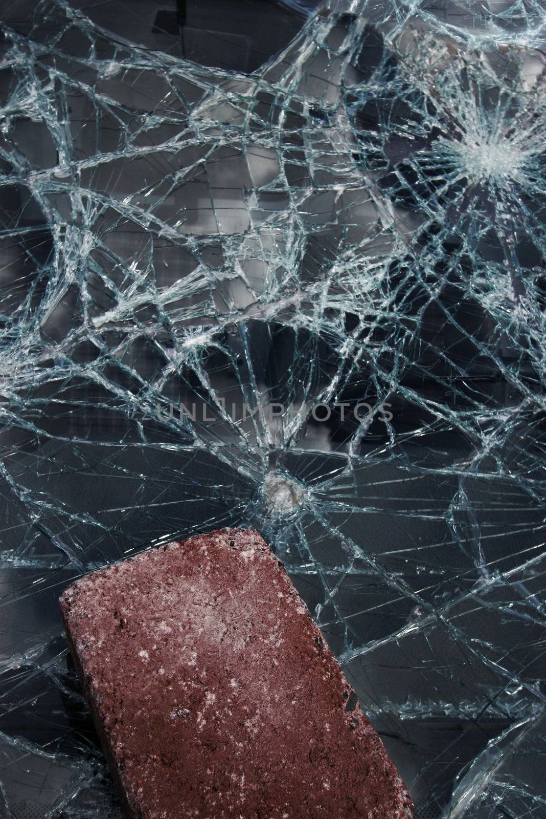Big brick lying on a completely shattered windshield