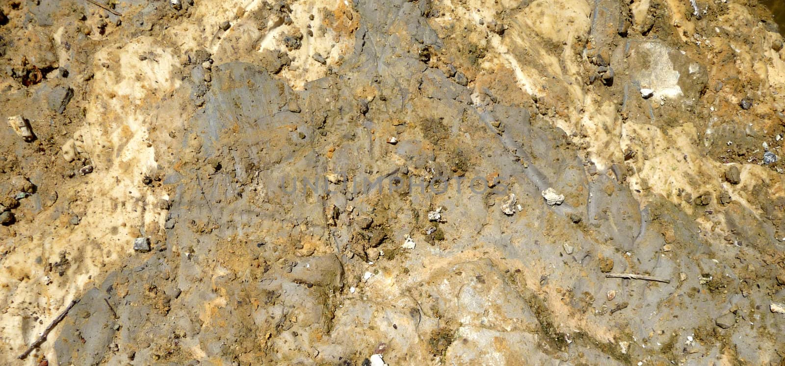 A abstract close up photograph of a bank of mud next to the water edge of a lake.