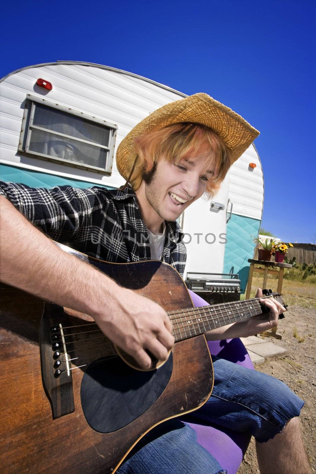 Young Man with Bright Red Hair and a Guitar in front of Trailer