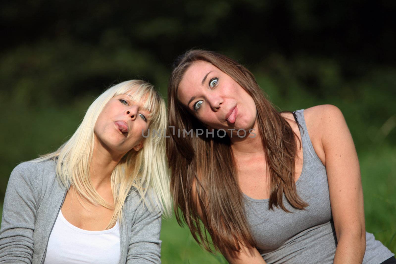 silly and funny young women stretch out your tongue. They wear casual clothes