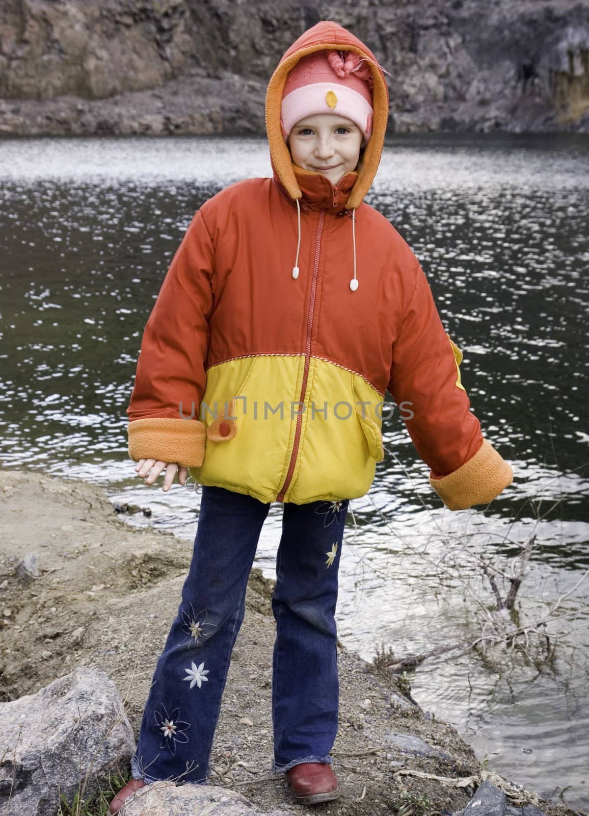 The girl in a red-yellow jacket plays lake