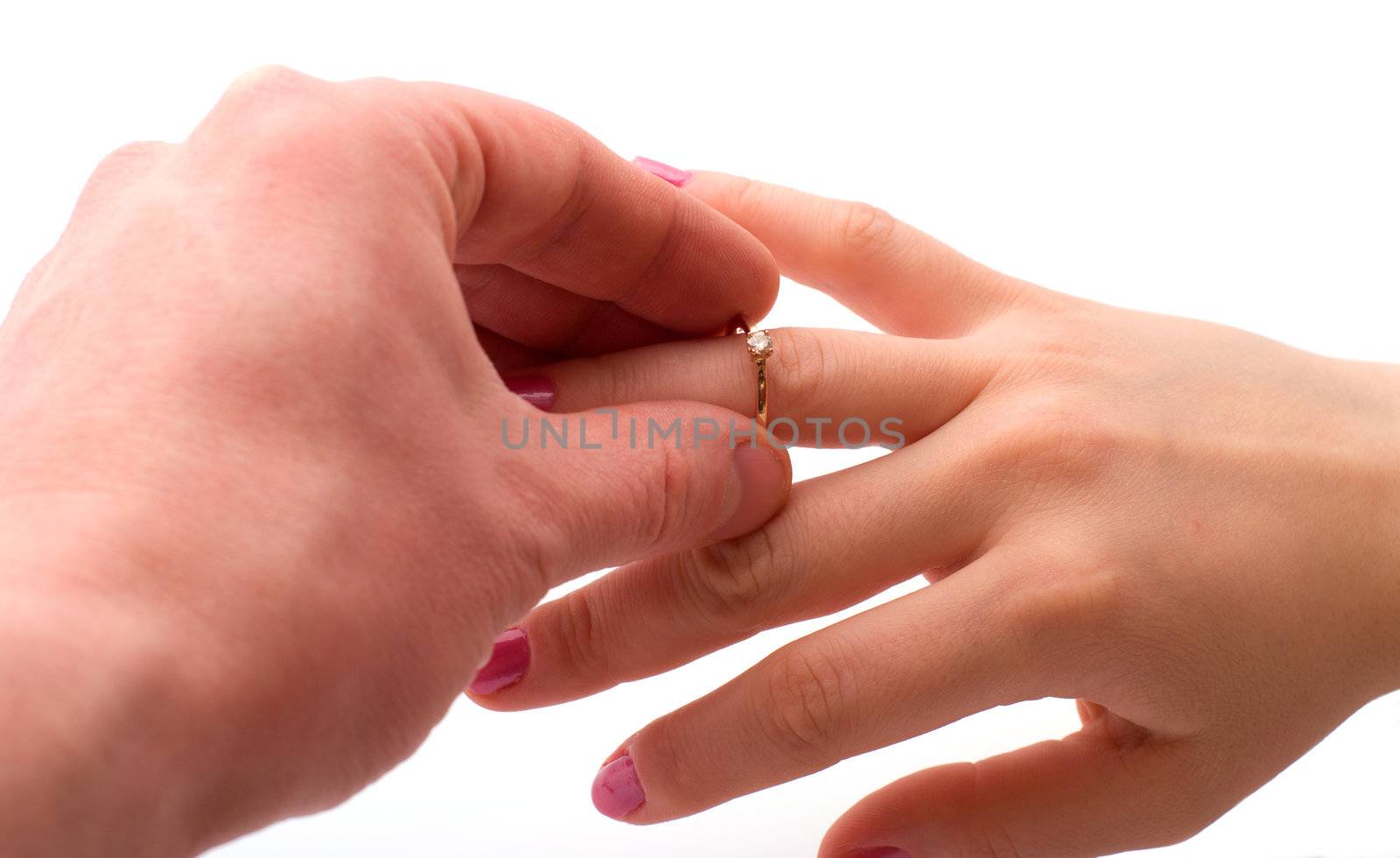 The man putting a gold ring with a brilliant on a female hand, is isolated on a white background.