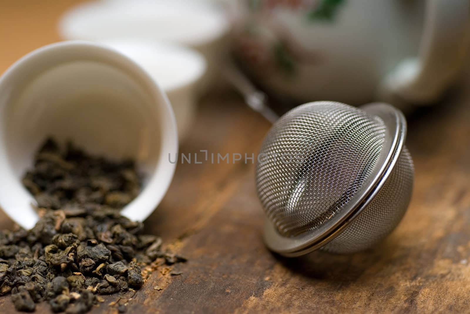 dry green chinese tea set,with strainer closeup,cups and teapot on background over old wood board