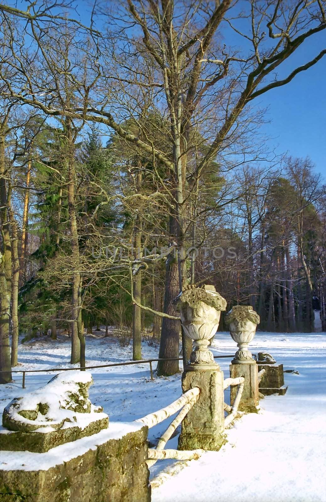 Fence with stone vases and ruin of sculpture in winter park