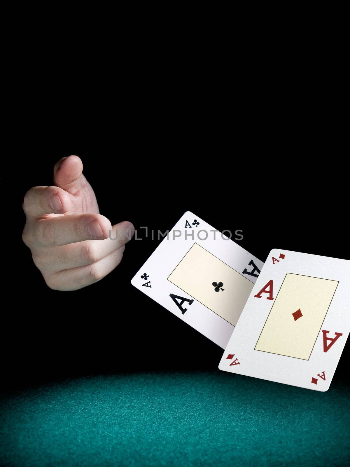 A man's hand throwing two aces over a green felt.