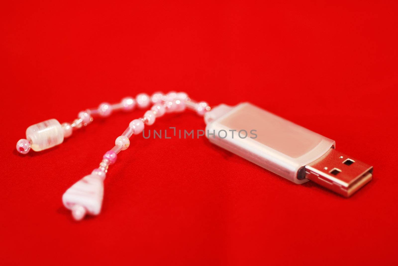 A close up photograph of a memory stick with a handmade bead charm attached.