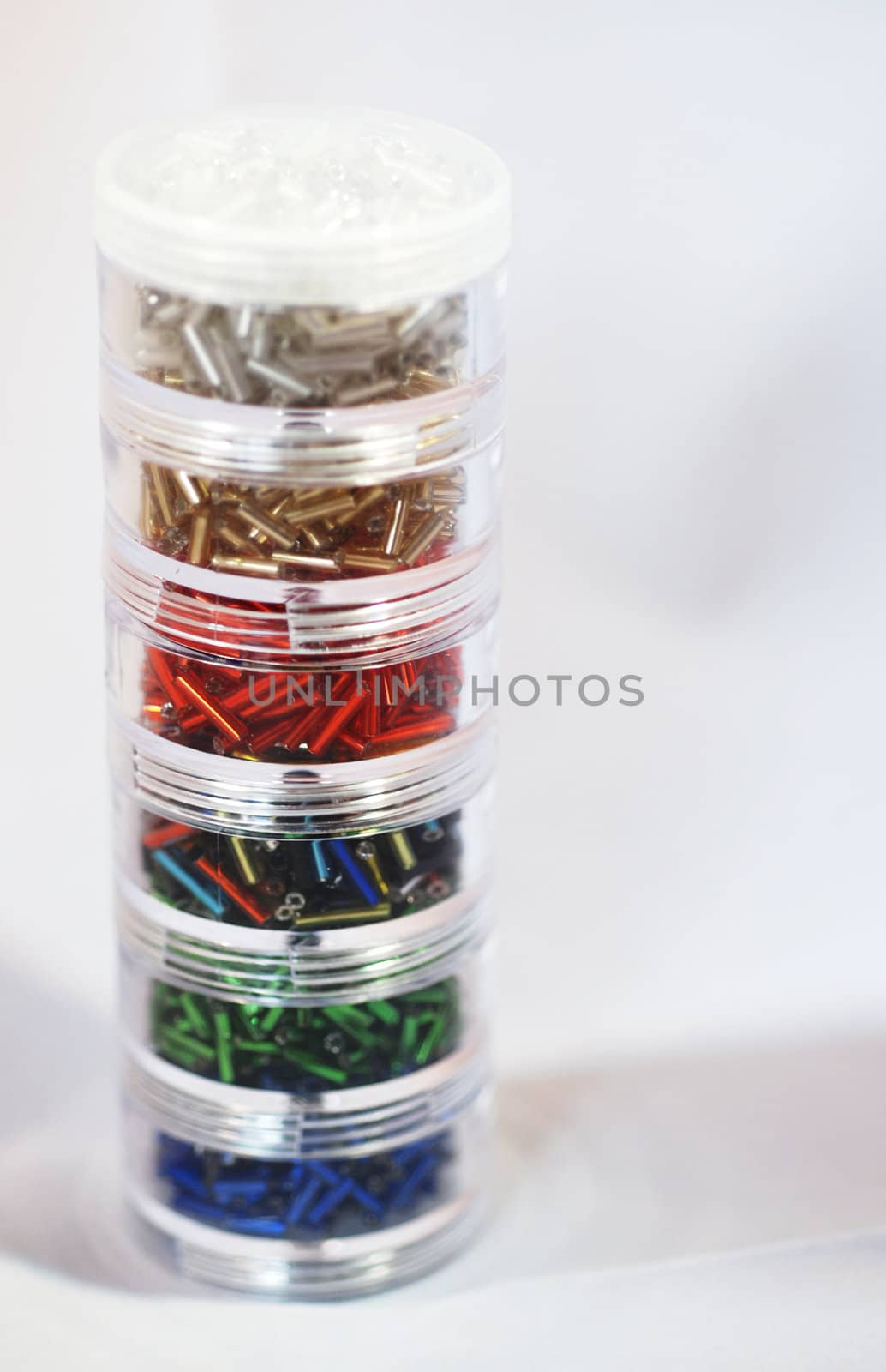 A close up photograph of a pile of jars of decorative bugle beads