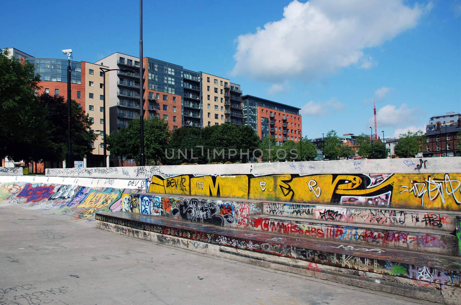 A photograph of the juxtaposition of a highly graffitied wall, against modern new developments and upmarket properties in a city centre.