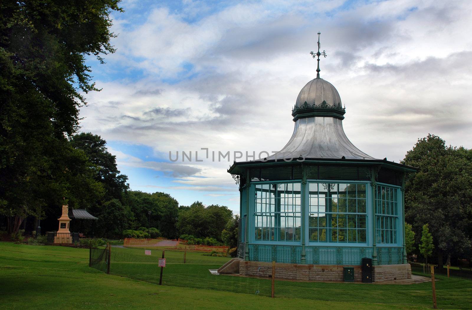 A photograph of a bandstand in a public park, under a stormy summer sky