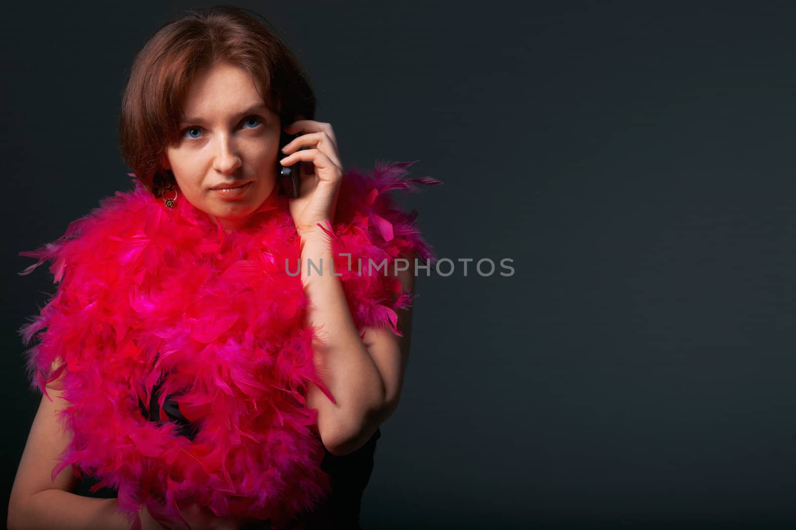 Beautiful woman in pink feathers speaks on phone. Close-up view